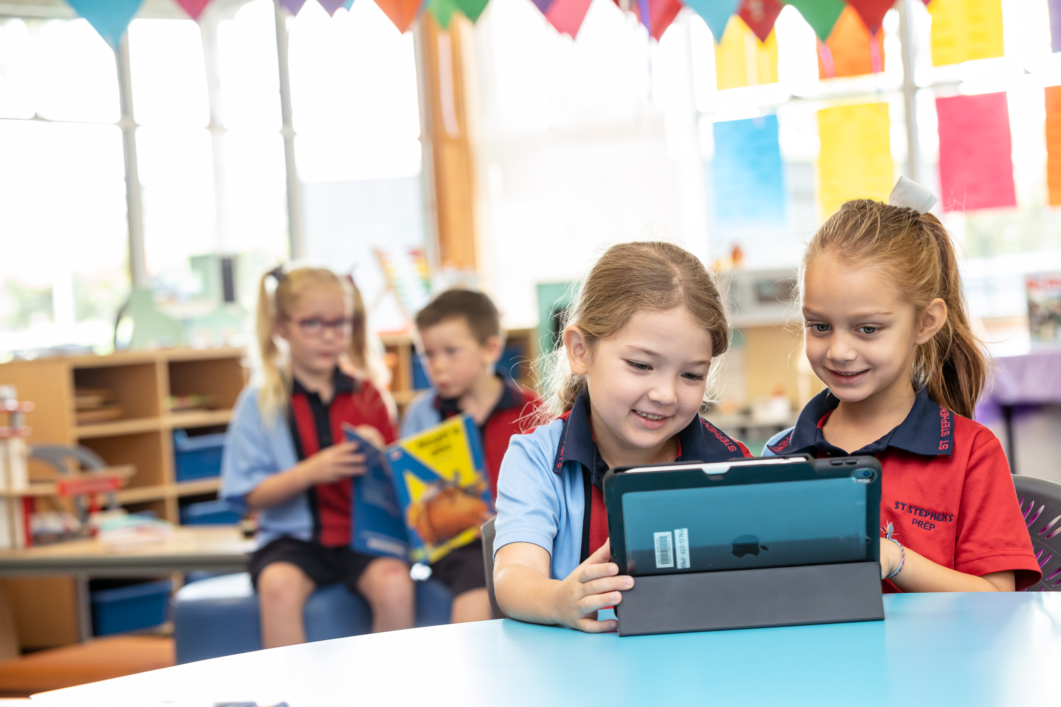 Two students sitting at a desk and working from an ipad.