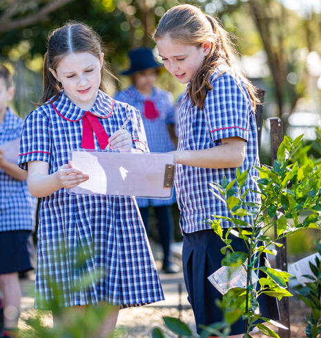 Two students outside, working from a clipboard.