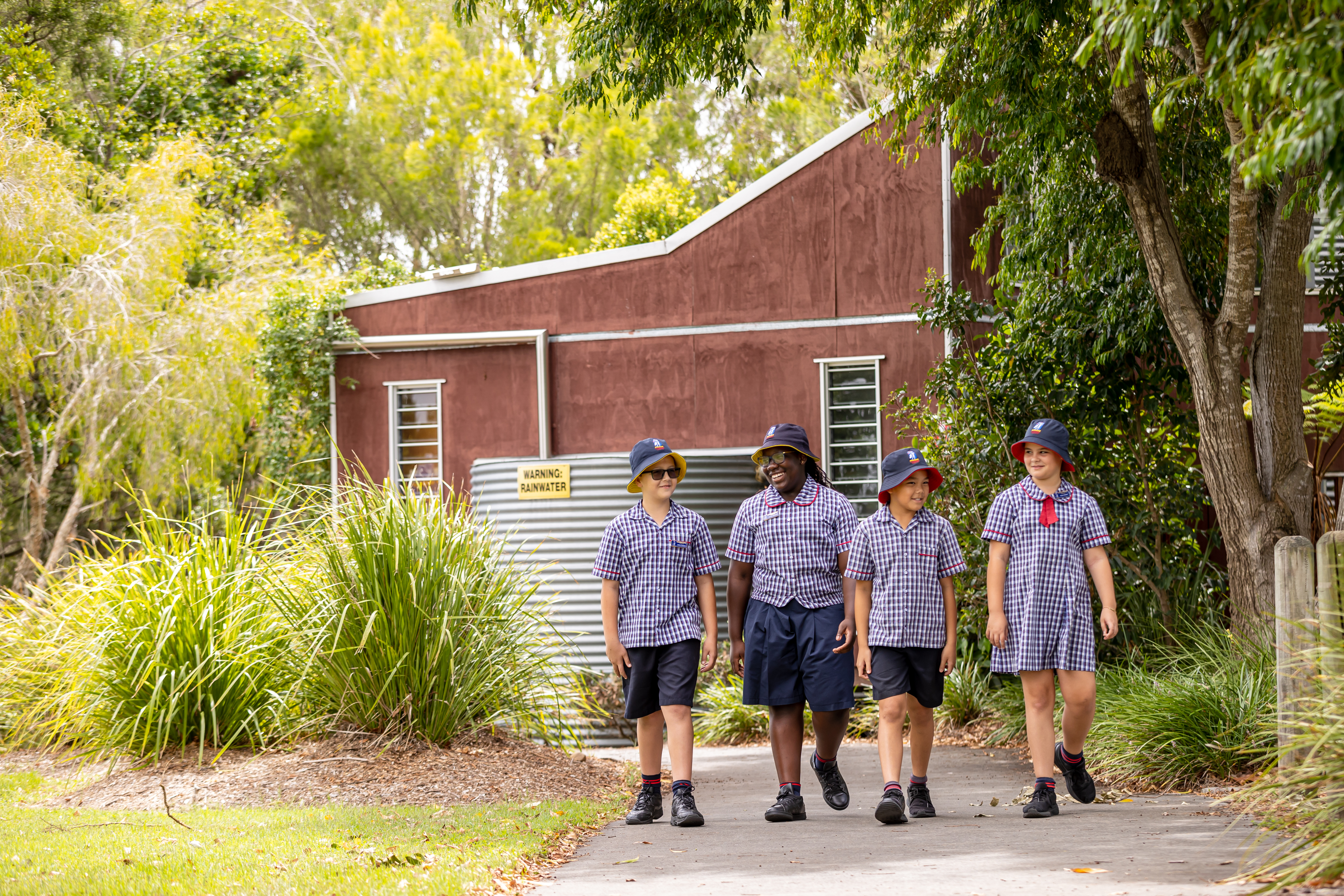 Four students outside walking along a path.